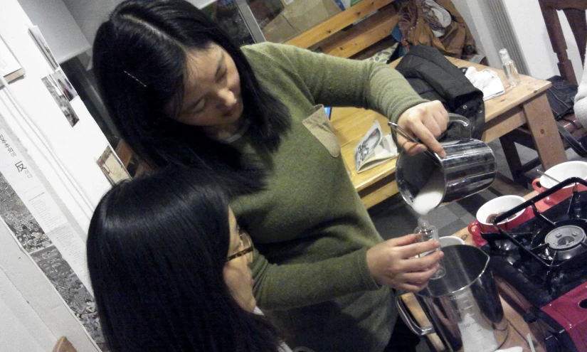 two women in green shirts are making beverages