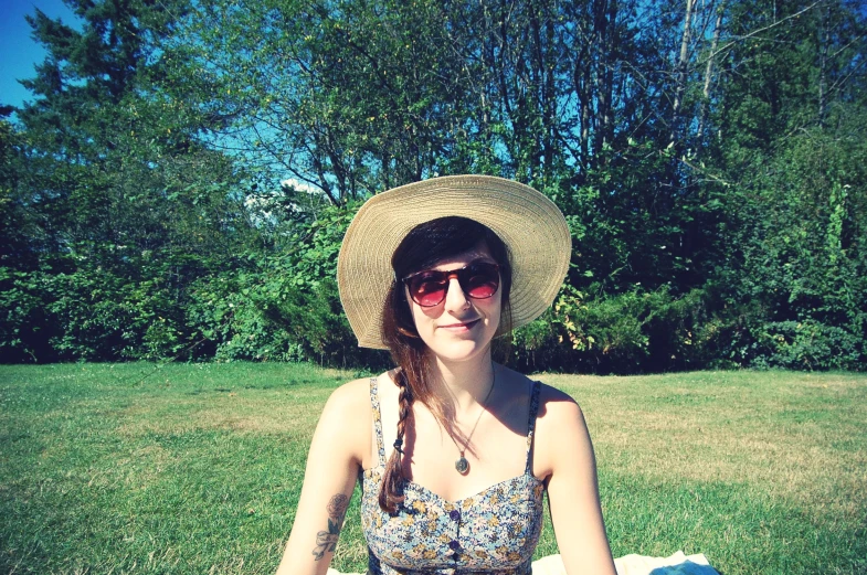 a woman sitting in the grass with sun glasses on