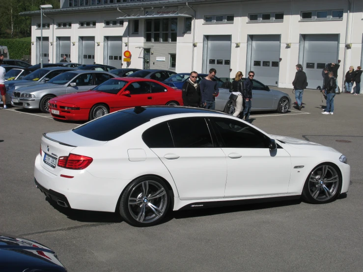 a white car is parked in front of a building with people