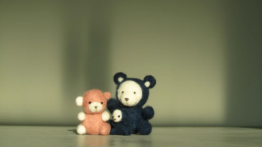 two teddy bears sit side by side against a wall