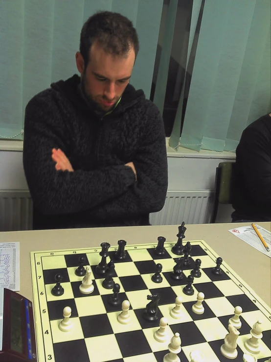 a man stands behind a chess board while another man looks at it