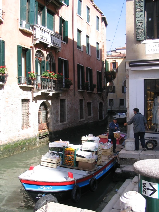 people loading boxes onto a boat in a canal