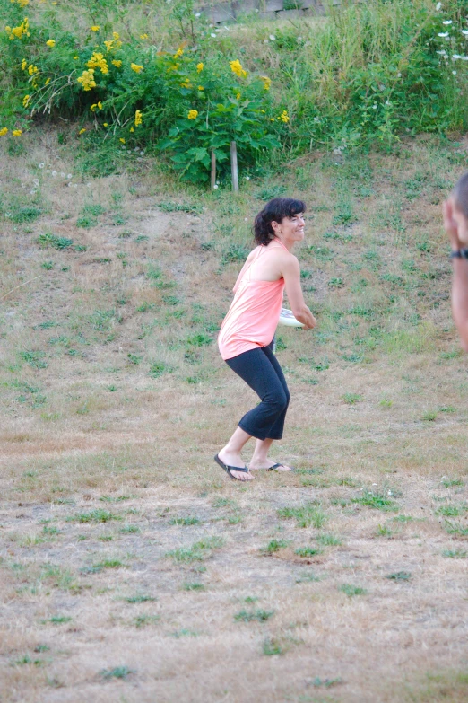 a woman standing in a field tossing a frisbee