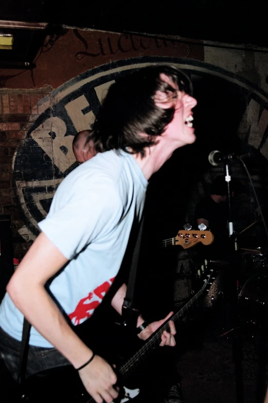 a person standing in front of a microphone and guitar