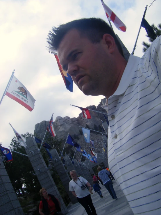 a man in a striped shirt next to some flags