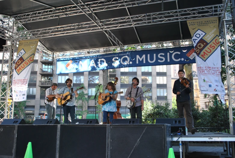 four people standing on a stage with their guitars in front of them