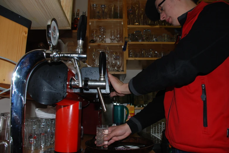 a man with a red jacket operating a coffee maker