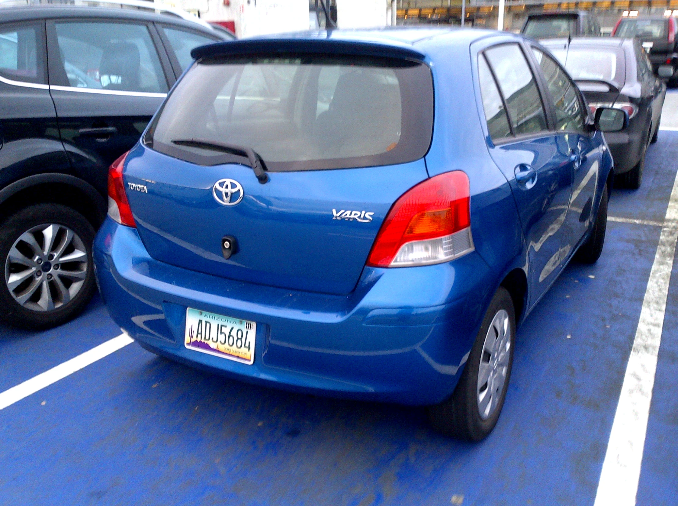 the rear end of a blue hatchback parked in a parking space