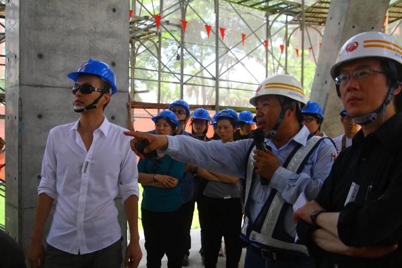 several construction workers having discussion in front of a group of people