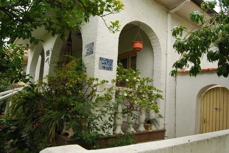 small white house with a yellow door, porch and plants