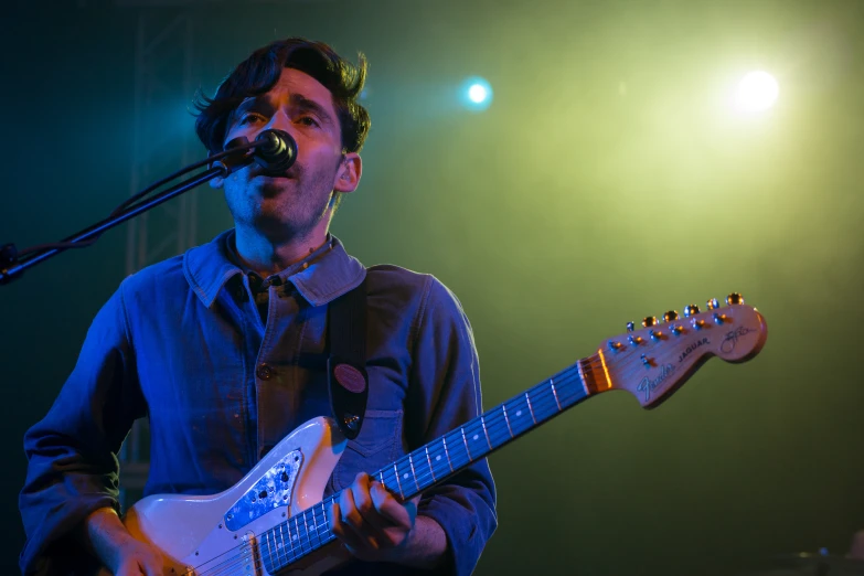 a man playing a guitar in front of a microphone