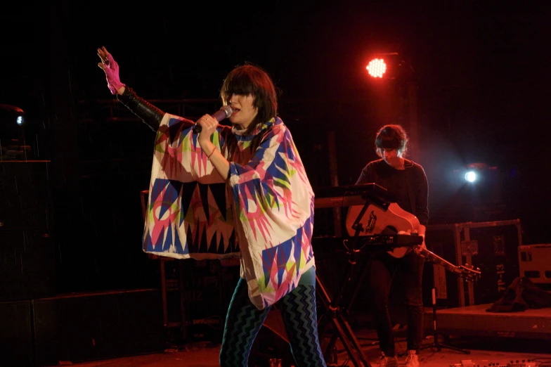 a woman in a psychedelic print shawl on stage