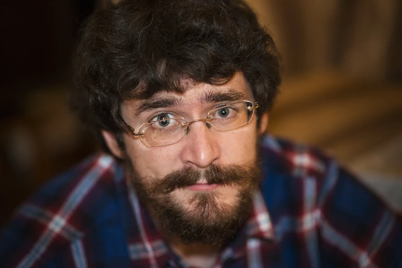 a man with glasses and a beard stares intently at the camera