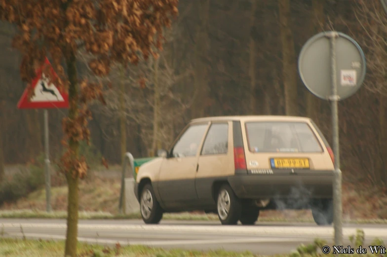 an orange and tan vehicle smoking a cigarette on the road