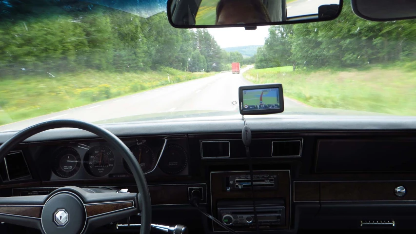 a dash view from inside the car showing trees and grass