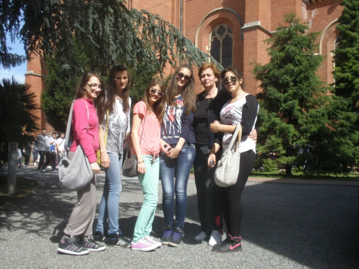 a group of young women standing in front of a tall brick building