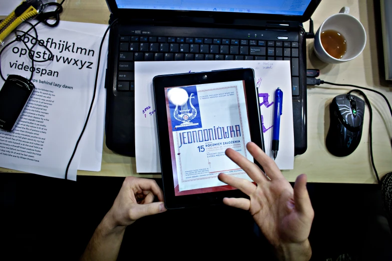 someone's hand on an open tablet on a desk