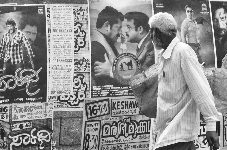 a man walking in front of large posters