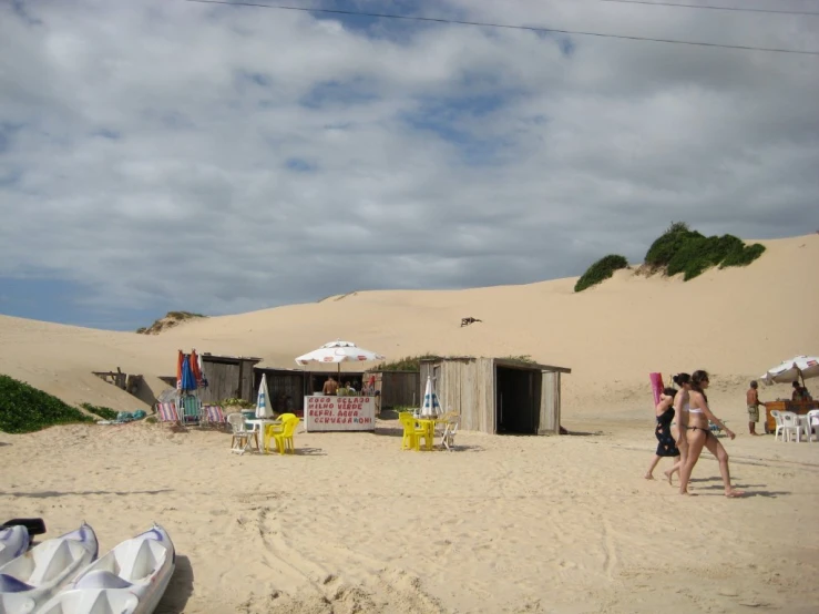 people on the beach near shacks and sand dunes