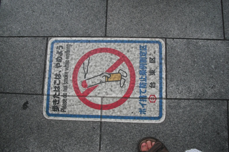 a sign stating no smoking while people walk across it