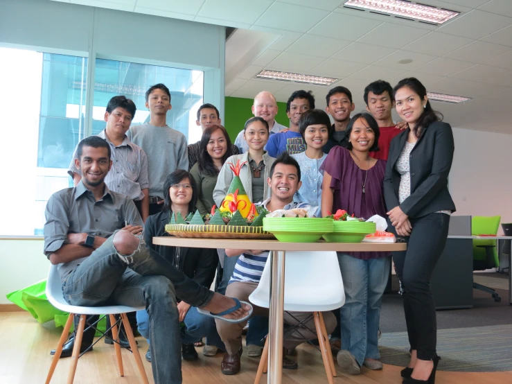 a group of people posing for a po while it is surrounded by a cake