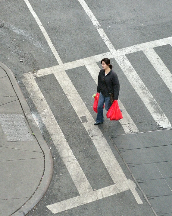 a man is crossing the street holding bags