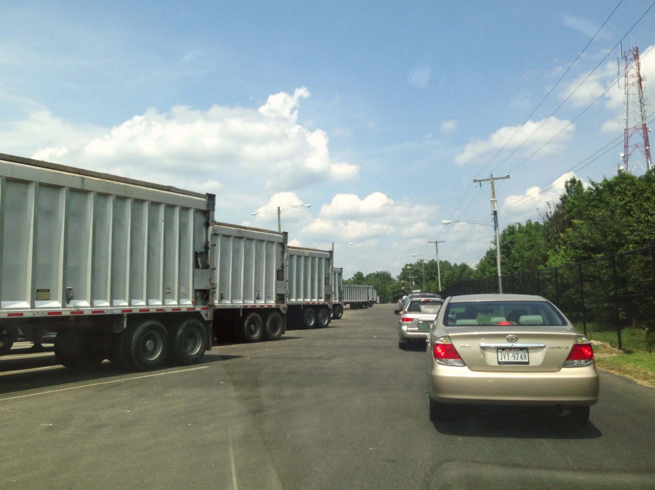 a silver car driving down a highway next to large trucks