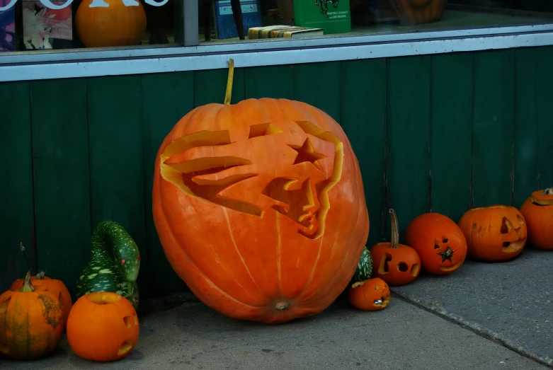 an elaborate carved pumpkin sits in front of many small pumpkins