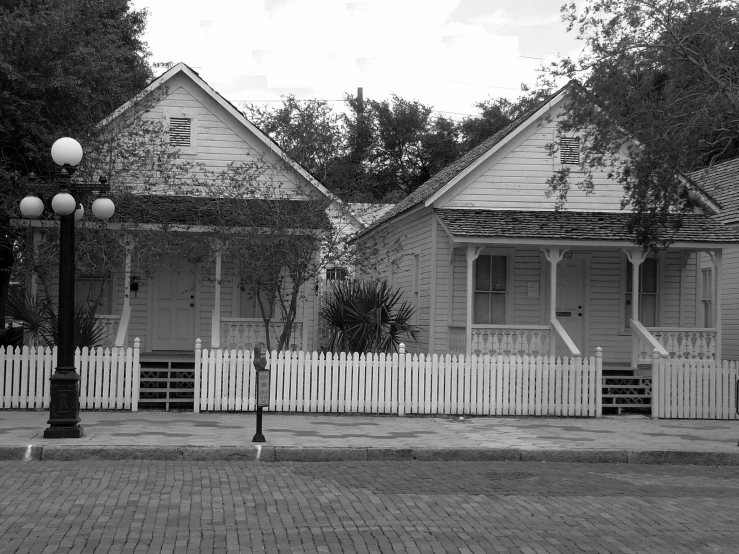 a black and white image of two houses with picket fence