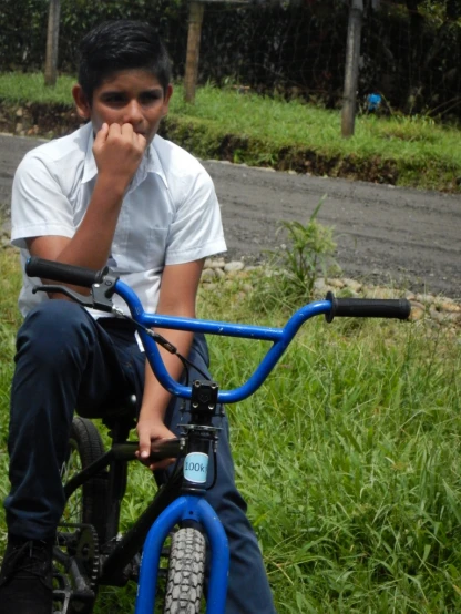 a boy with a white shirt sitting on a blue bicycle
