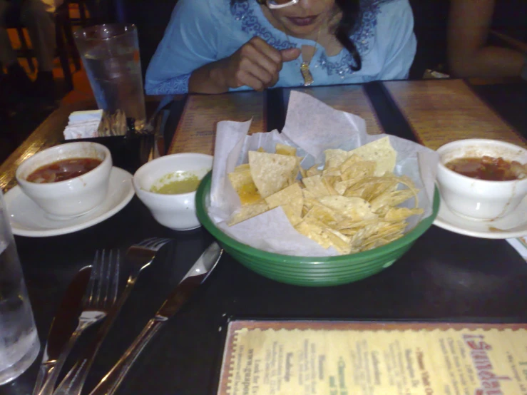 a plate filled with chips and salsa next to bowls of dips