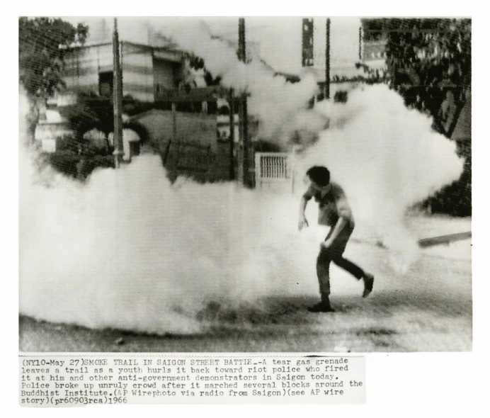 a man playing with a smoke bomb while standing next to a building