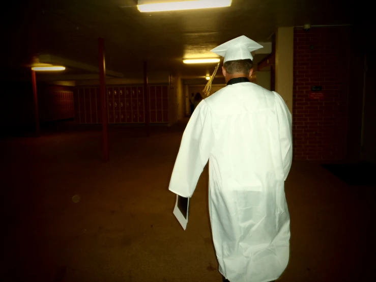 man in white suit and cap walking down a hall