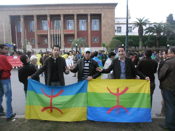 people stand behind two large flags holding up flags