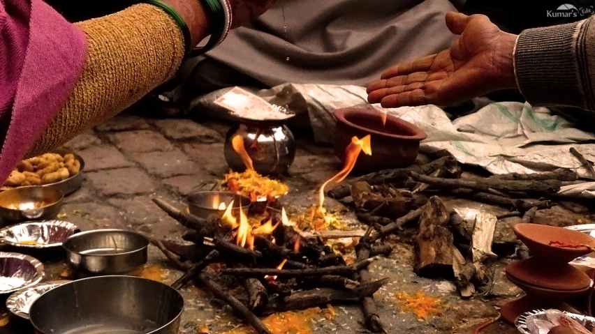 someone standing over a fire pit with cooking utensils