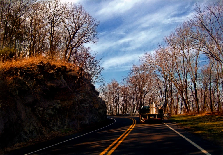 a semi is driving down the road with a hill on the side