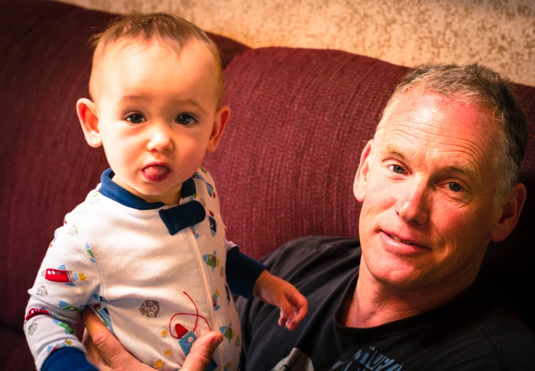 a man holding a baby while sitting on a couch