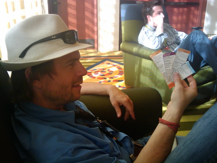 man in a hat sitting on a coach looking at a newspaper