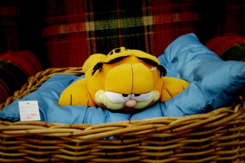 a stuffed toy with a sad face is laying in a wicker basket