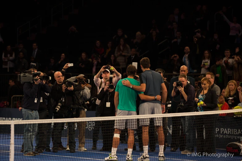 two tennis players hugging each other in front of spectators