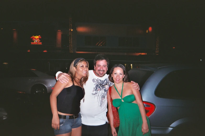 four people pose together in front of a car