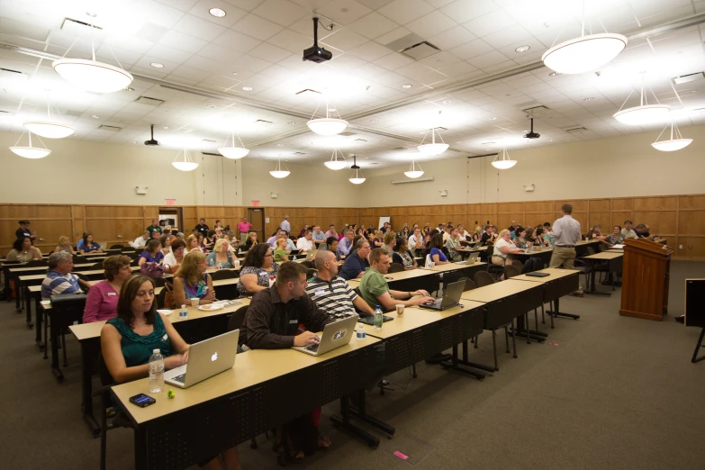 people sit at large tables in a classroom and talk