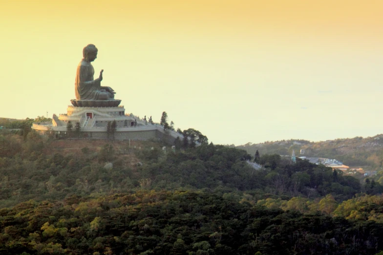 a large statue in a field on top of a hill