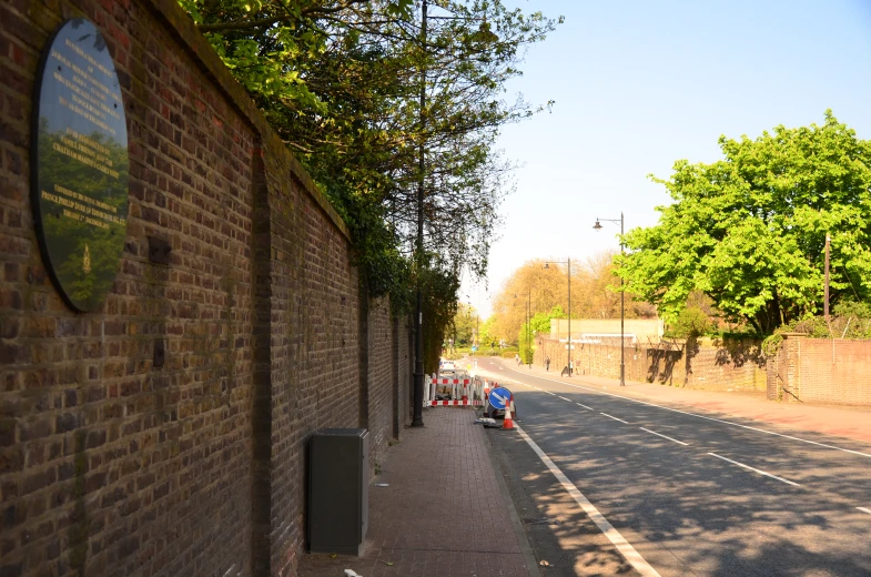 a brick wall with a sign on it near a street