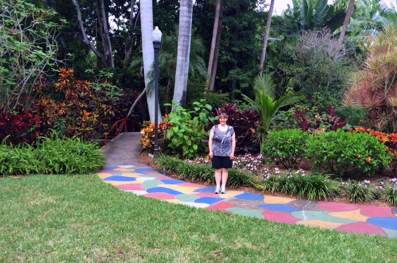 a woman stands on a sidewalk covered in multicolored tiles