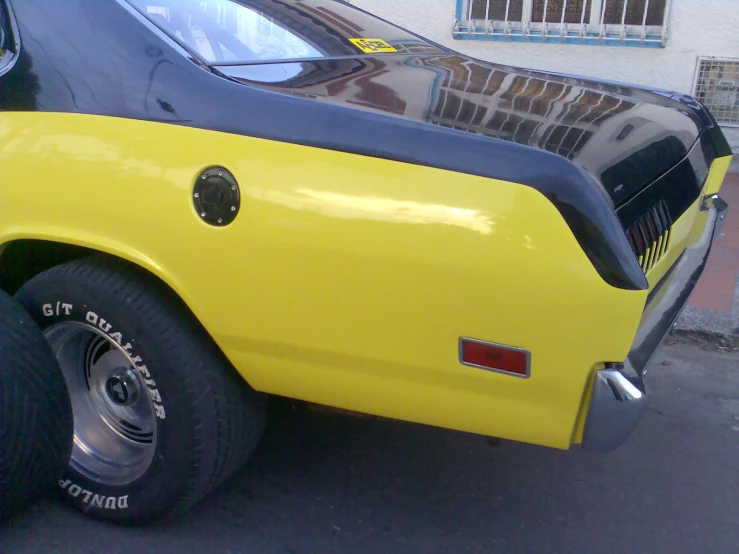 the rear end of a yellow sports car with black stripe