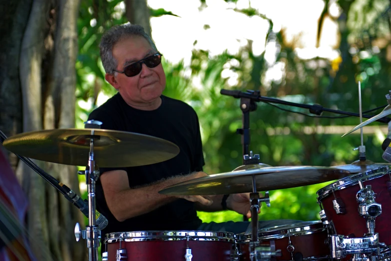 an older man with sunglasses playing the drums