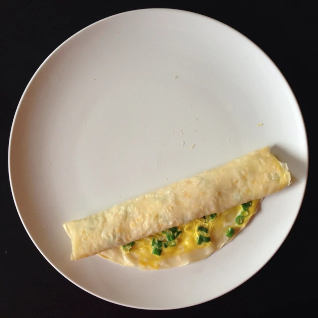 an omelette on a white plate on a black table