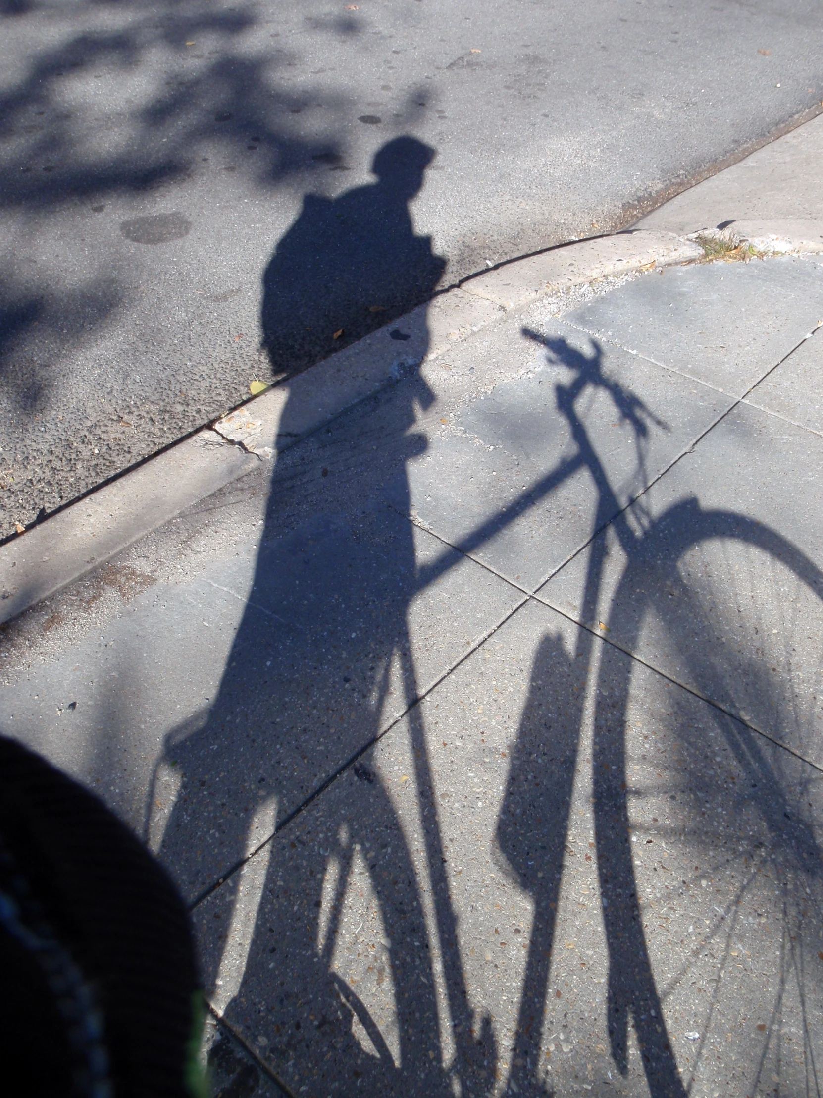 the shadow of a man with his bicycle on the street