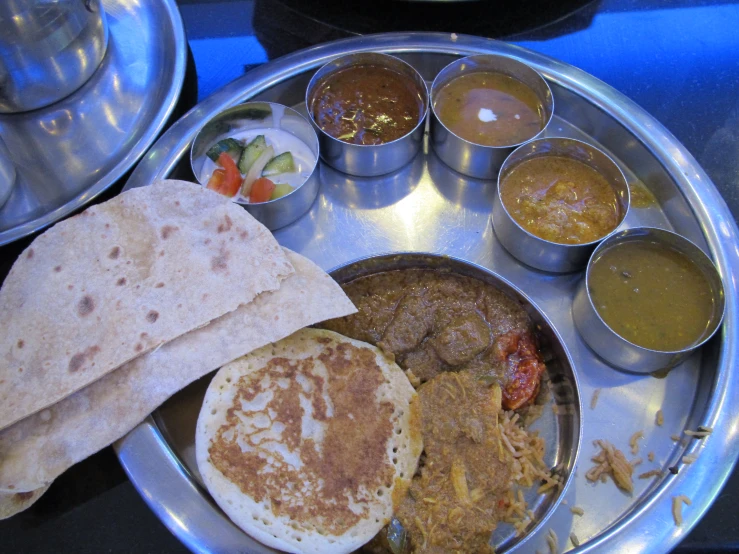 plate of food with a flatbread, soups, and other side dishes on it